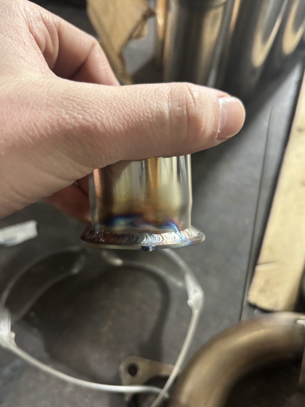 TIG weld on a stainless exhaust flange, heat tint visible